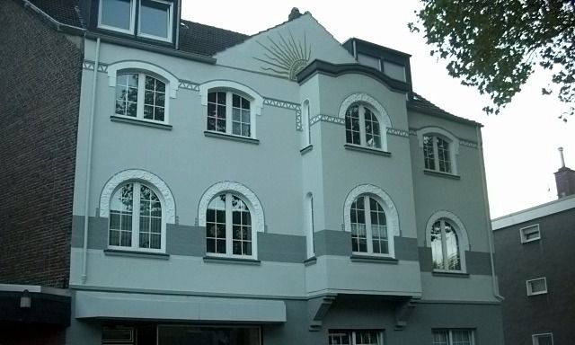 Altbau mit Rundbogenfenstern und Stuck, Fassade in hellem Grün mit grau abgesetzten Bändern