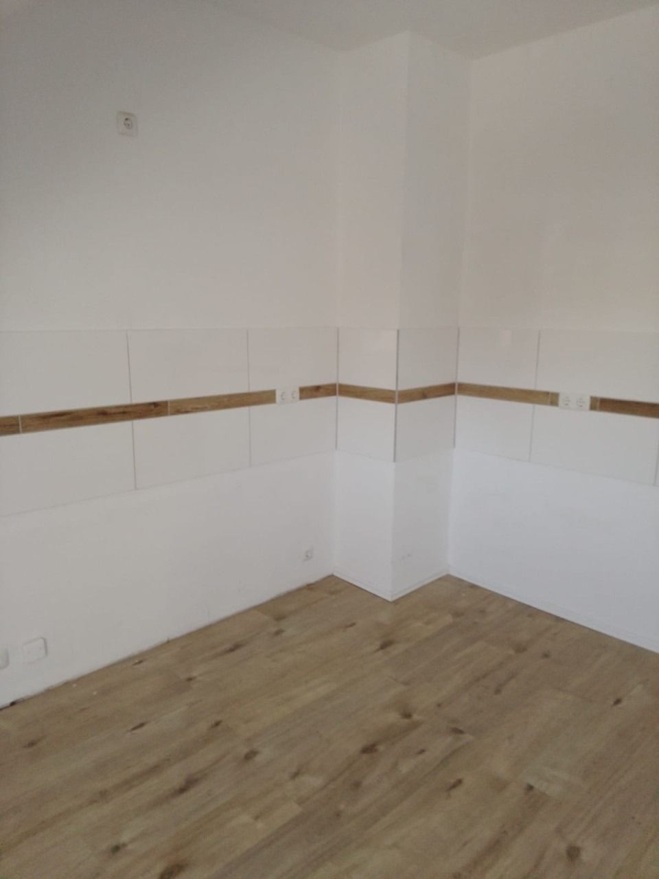 Heller Dachgeschossraum mit weißen Wänden, Fliesenspiegel und Boden in Holzoptik