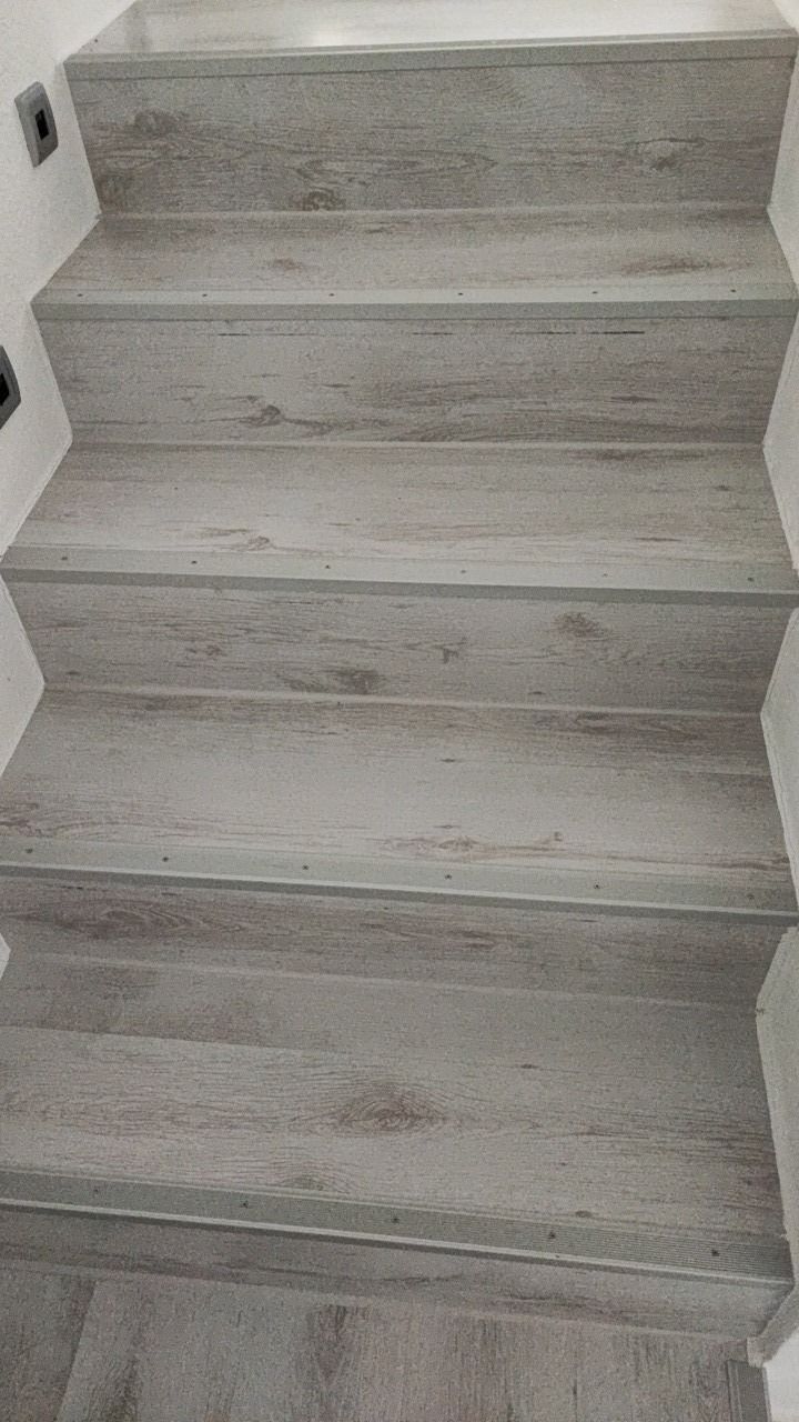 Treppenstufen mit grauem Belag in Holzoptik, von oben fotografiert