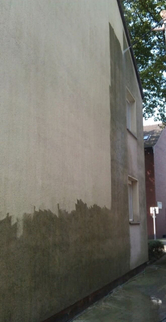 Hauswand, deren obere Fläche hell gereinigt und deren untere Fläche noch dunkel verschmutzt ist